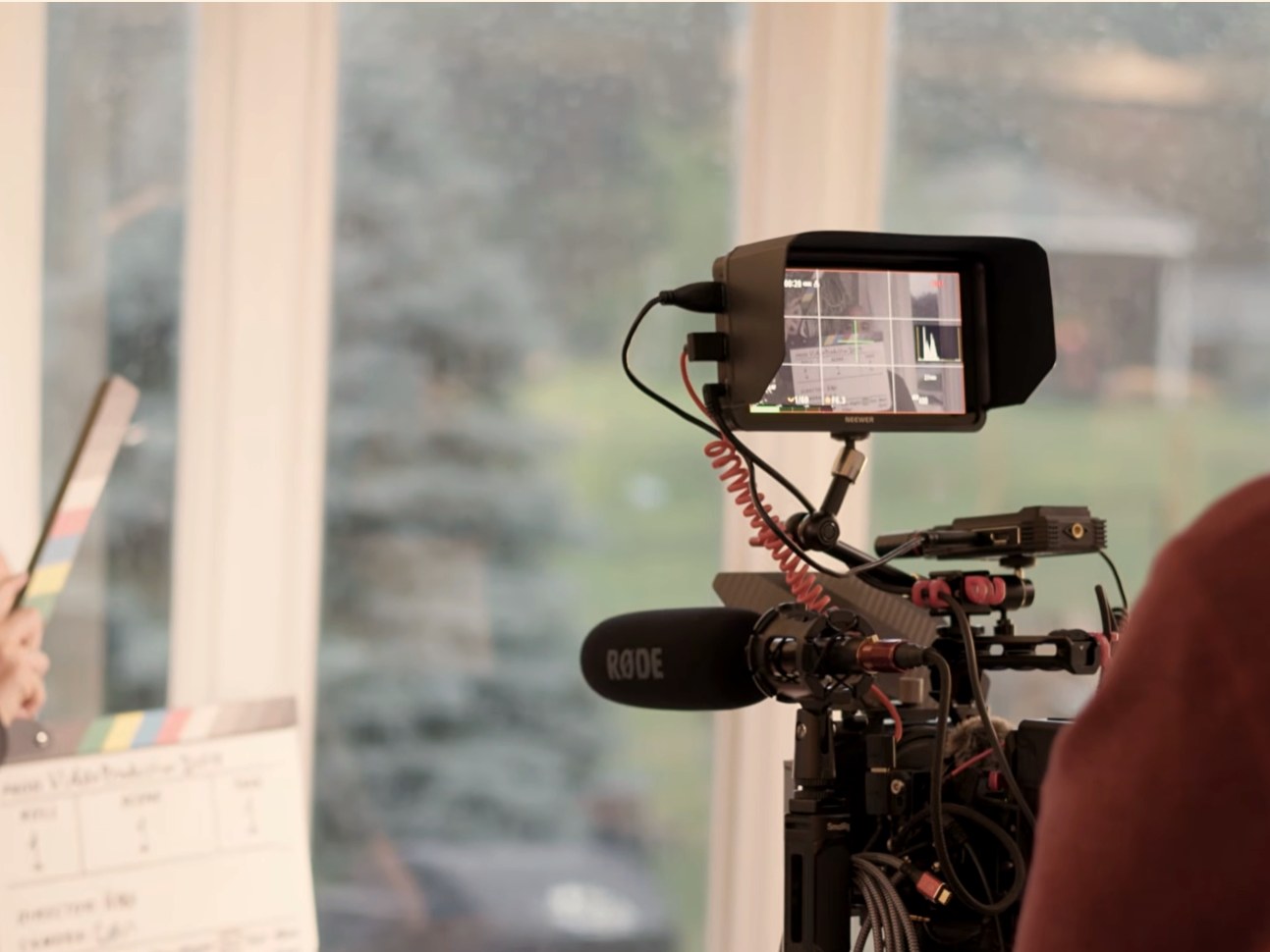 Camera monitor and shotgun mic framing a documentary interview